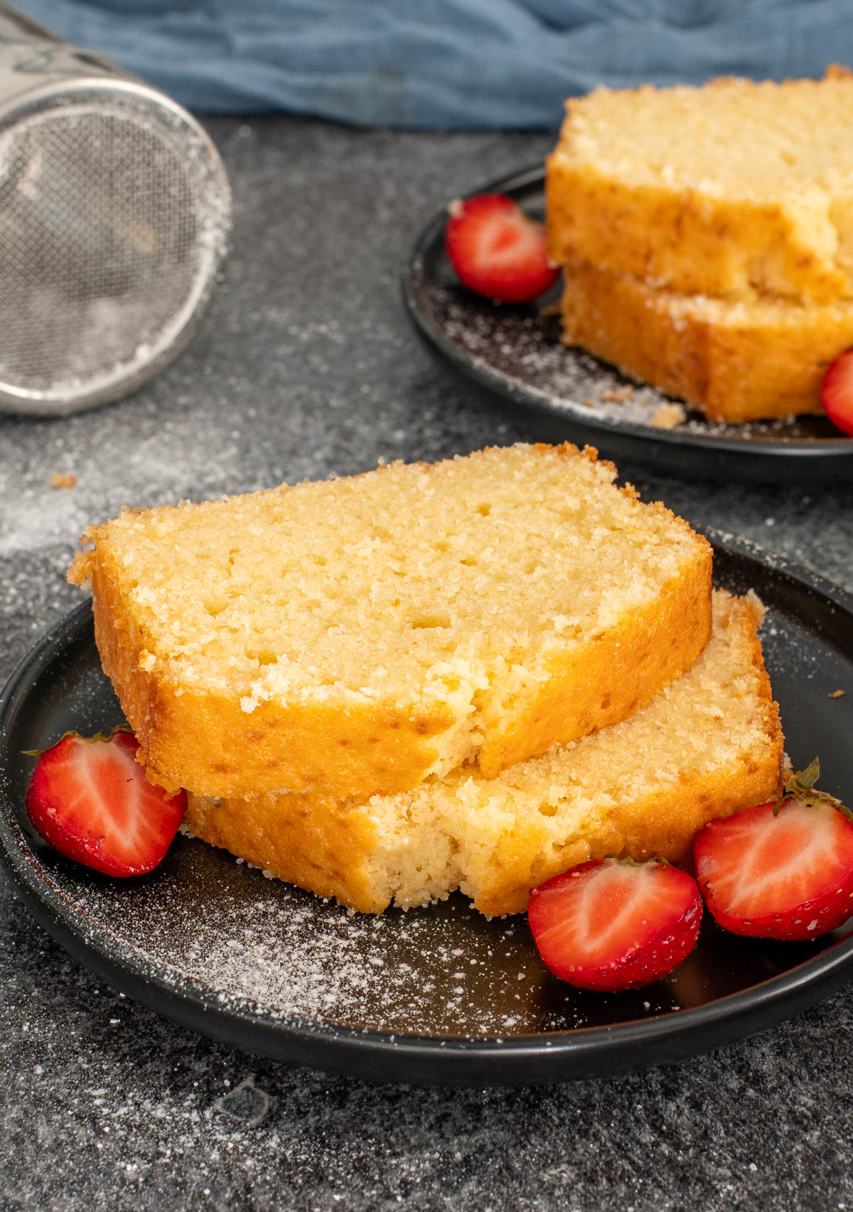 Doua felii de pound cake servite alaturi de capsuni proaspete.