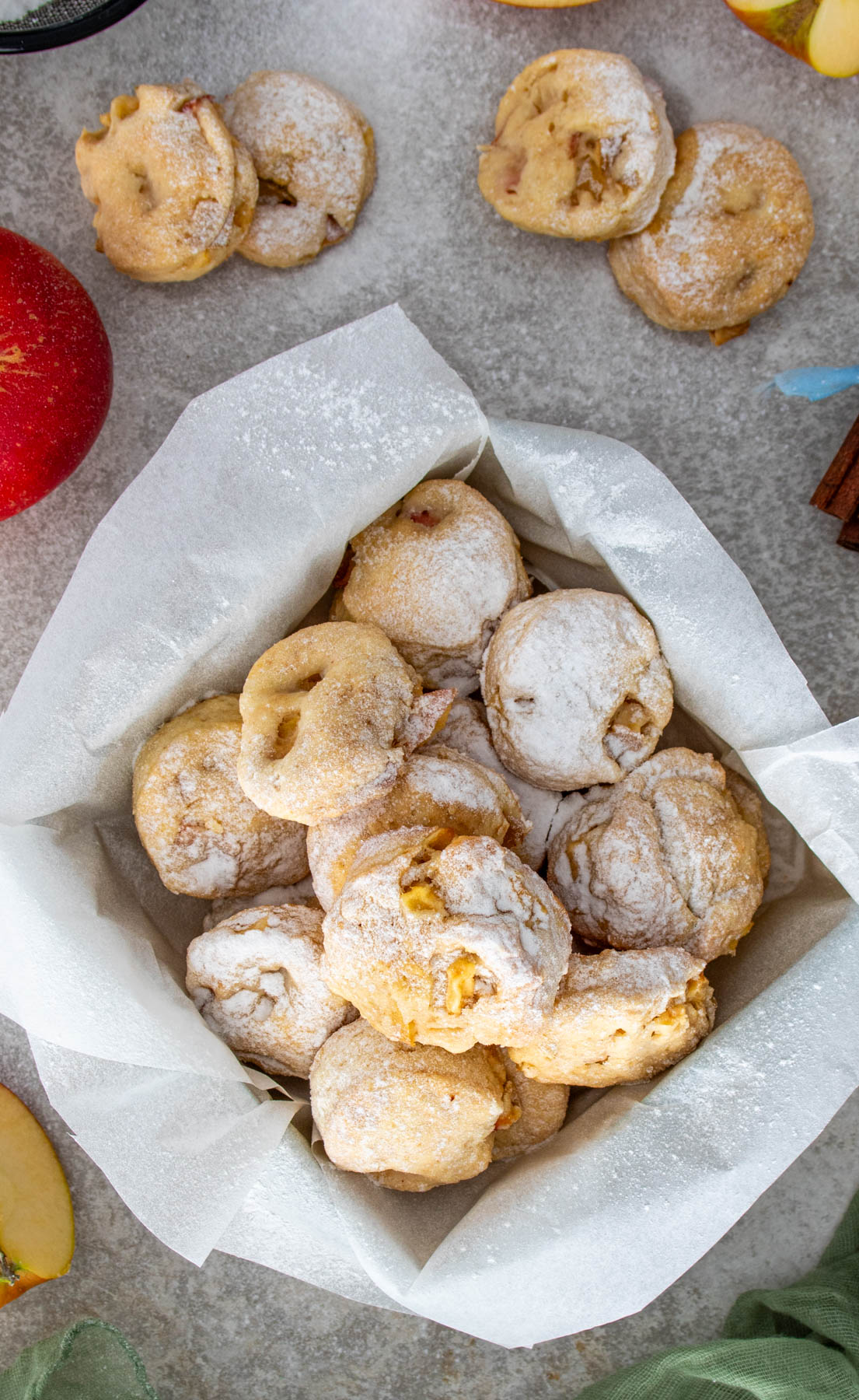Biscuiți pufoși cu mere și scorțișoară, pudrați cu zahăr, așezați într-o cutie decorată de sărbători.