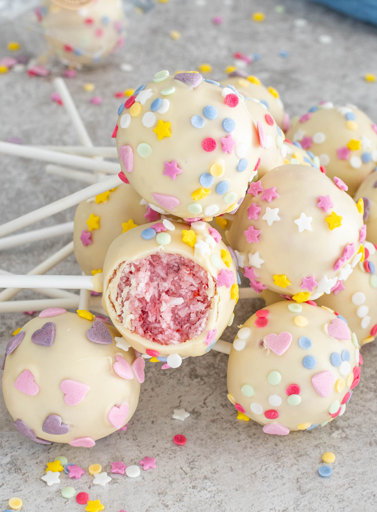 Deserturi mici din cocos si zmeura cu ciocolata alba si unul cu o muscatura.