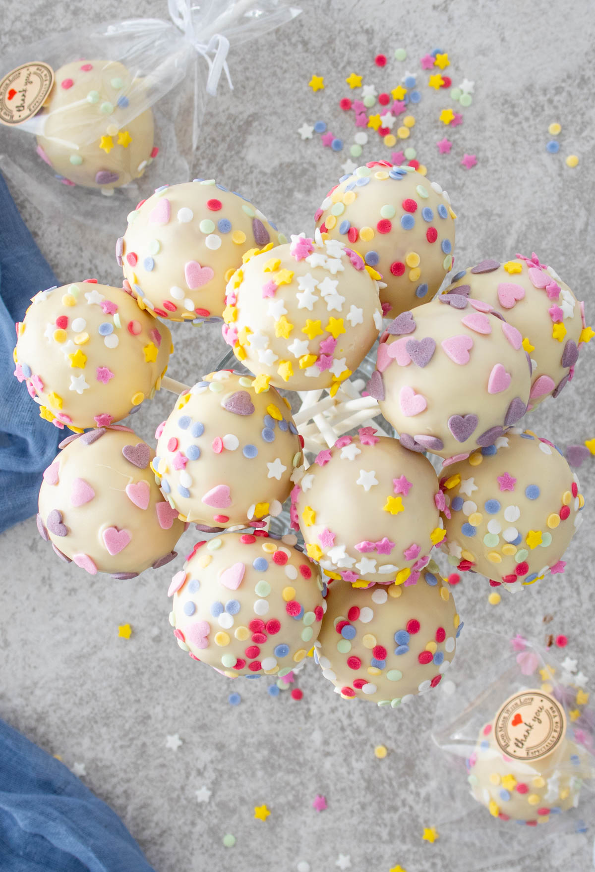 Pahar cu 12 cake pops cu cocos, zmeura si ciocolata alba, fotografiati de sus.