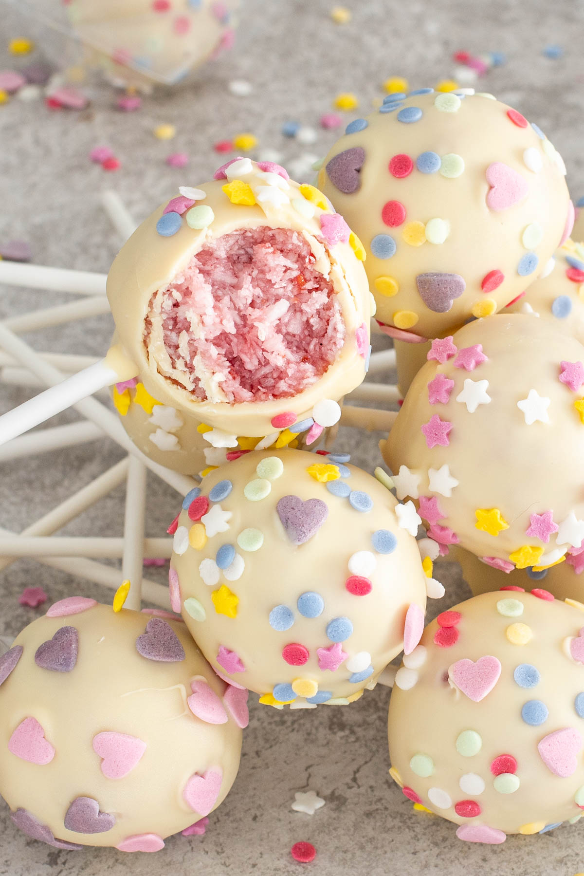 Cake Pops cu zmeura si cocos, cu unul sectionat pentru a vedea compozitia.