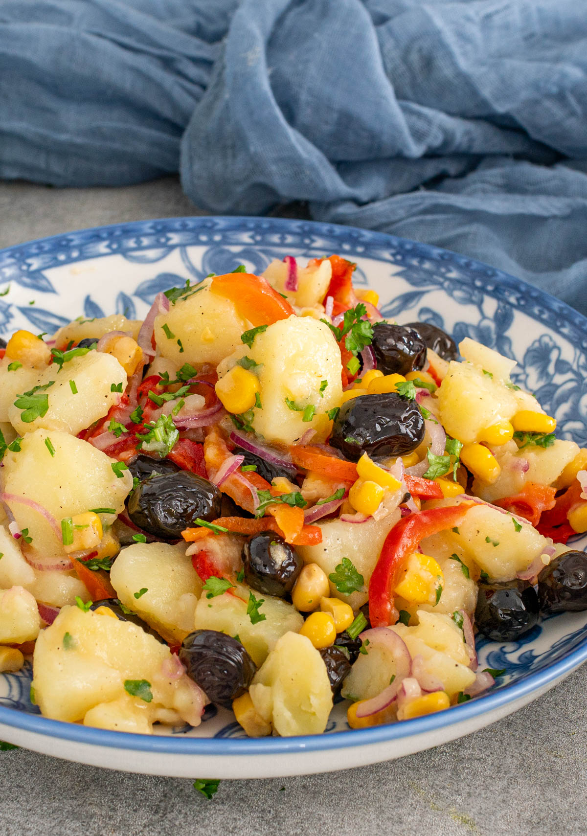 O porție generoasă de salată orientală de post, cu cartofi fragezi, gogosari murați, porumb dulce și măsline negre, presărată cu pătrunjel proaspăt.