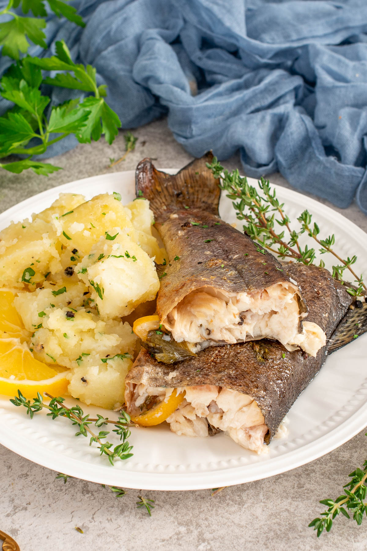 Păstrăv proaspăt la cuptor cu felii de lăm&acirc;ie și cartofi natur.