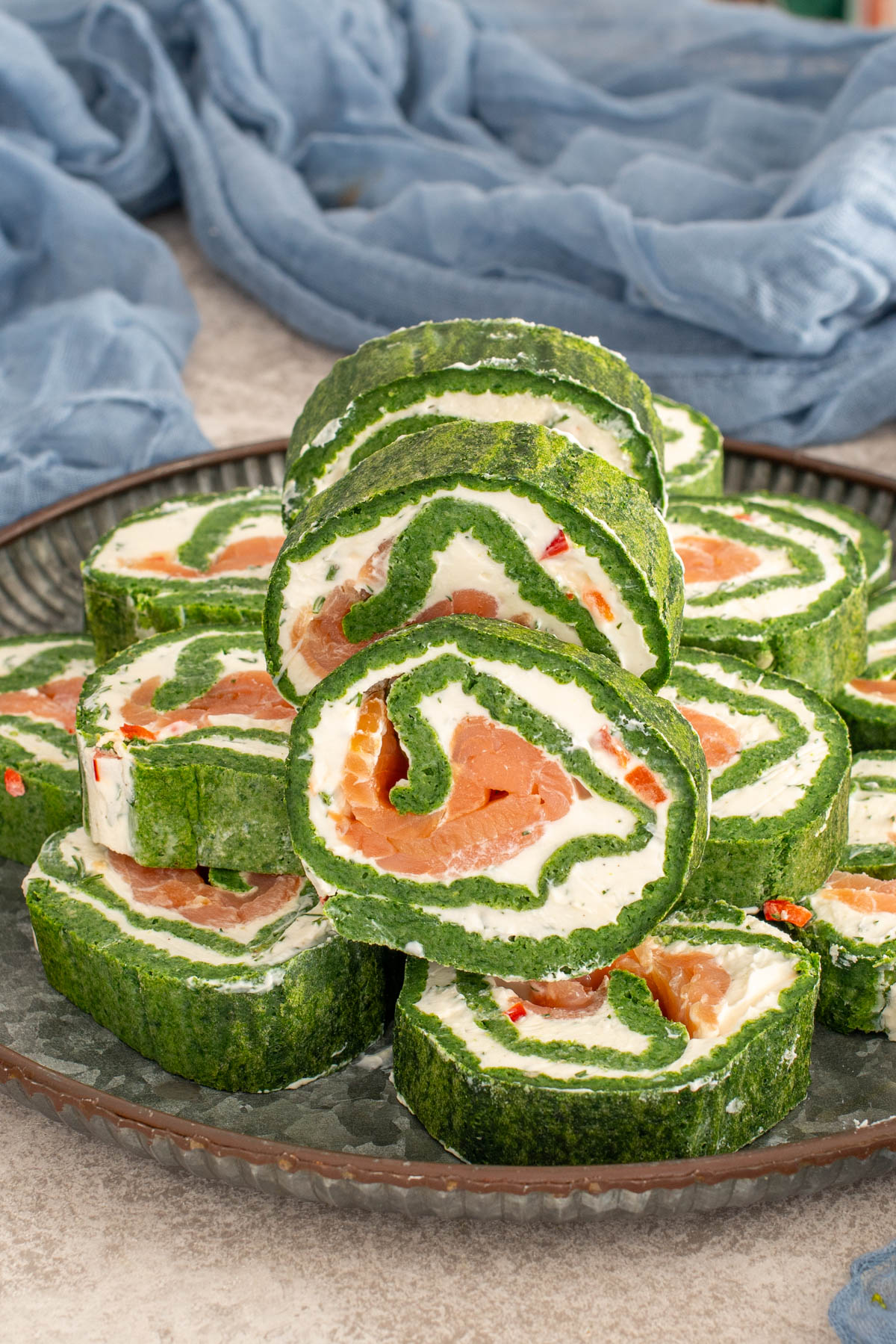 Ruladă de spanac cu cremă de br&acirc;nză și somon afumat. Un preparat proaspăt și colorat, const&acirc;nd &icirc;ntr-o rolă verde vibrantă de spanac umplută cu o cremă fină și felii de somon afumat.