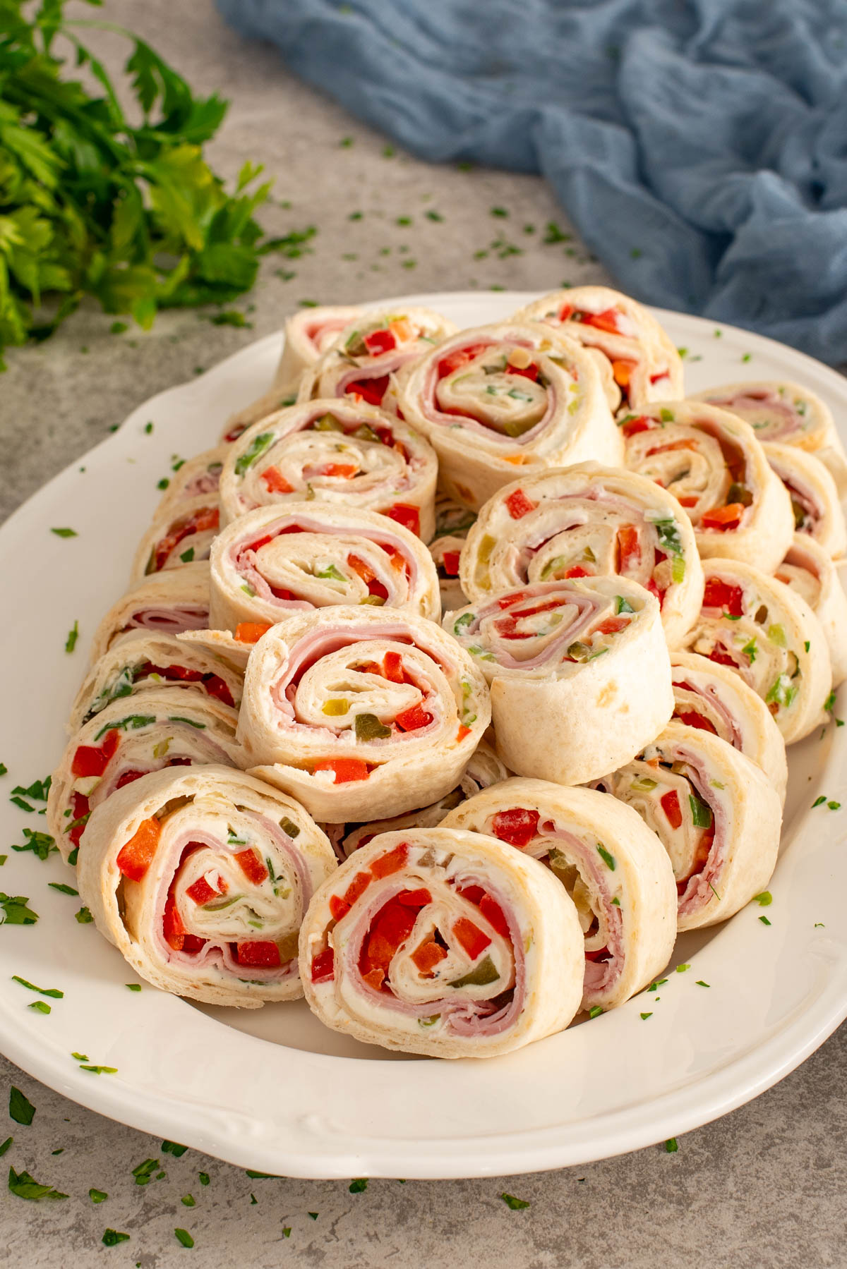 Platou alb cu rondele de rulada din tortilla cu crema de branza si sunca.