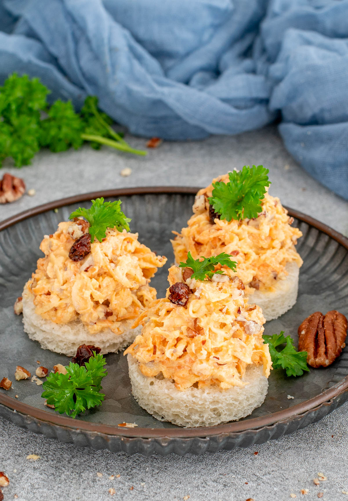 Salata de telina cu morcovi si mar servita pe felii de paine alba si decorata cu patrunjel , nuci si stafide.