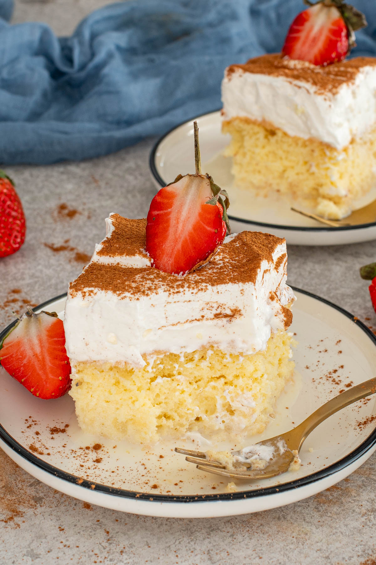 Felie de prăjitură Tres Leches cu frișcă, scorțișoară și căpșuni.