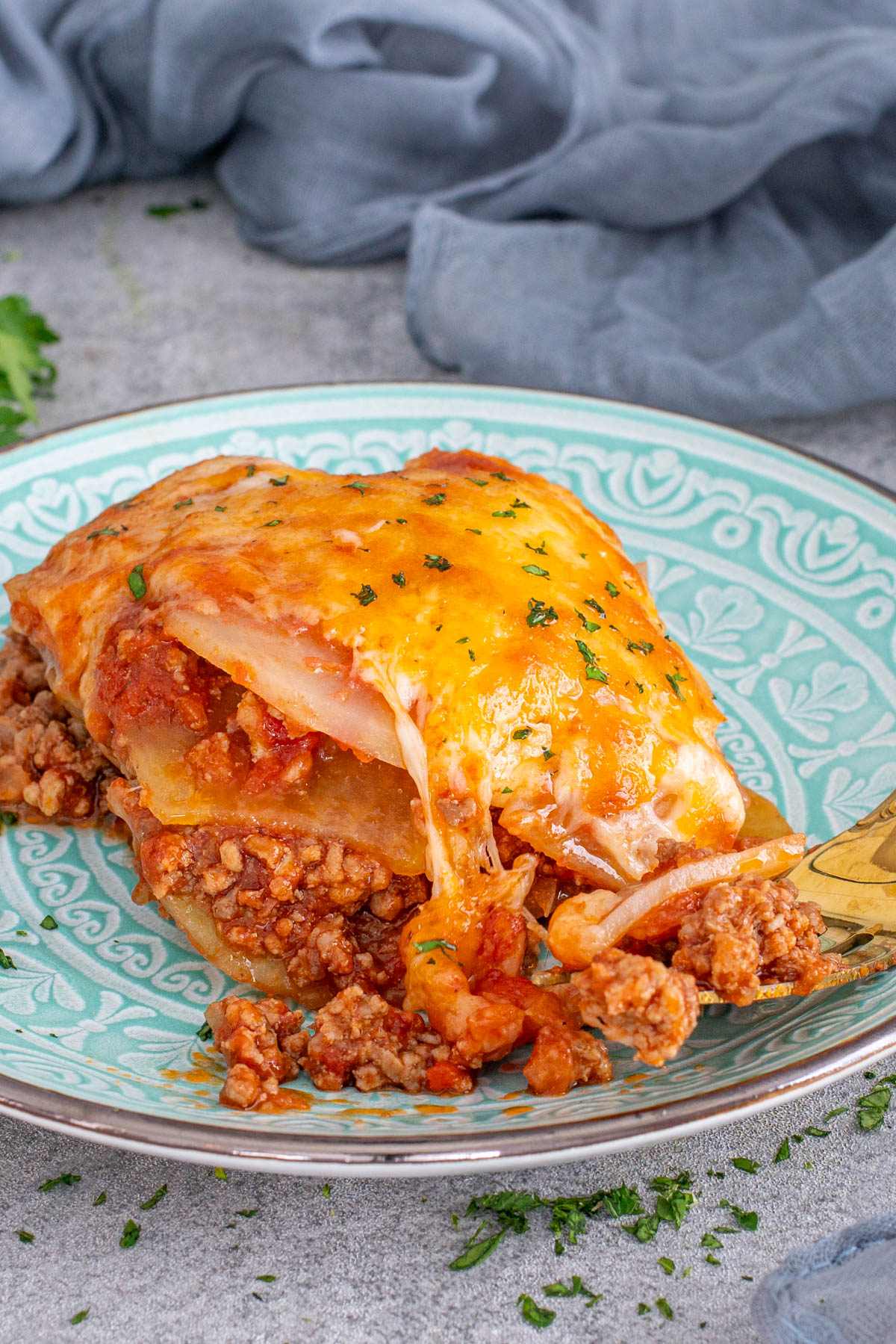 Porție de musaca așezată pe farfurie, gata de servit.