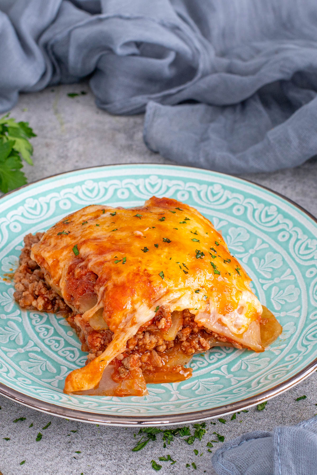 Porție de musaca așezată pe farfurie, gata de servit.