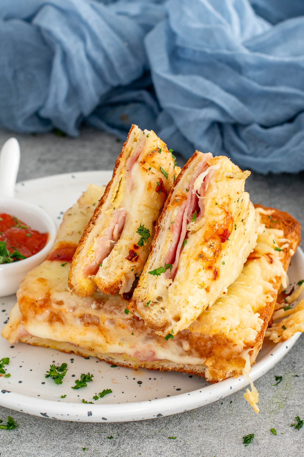 Sendvișuri gratinate cu p&acirc;ine &icirc;nmuiată &icirc;n ou, șuncă și br&acirc;nzeturi topite, rumenite perfect la cuptor.