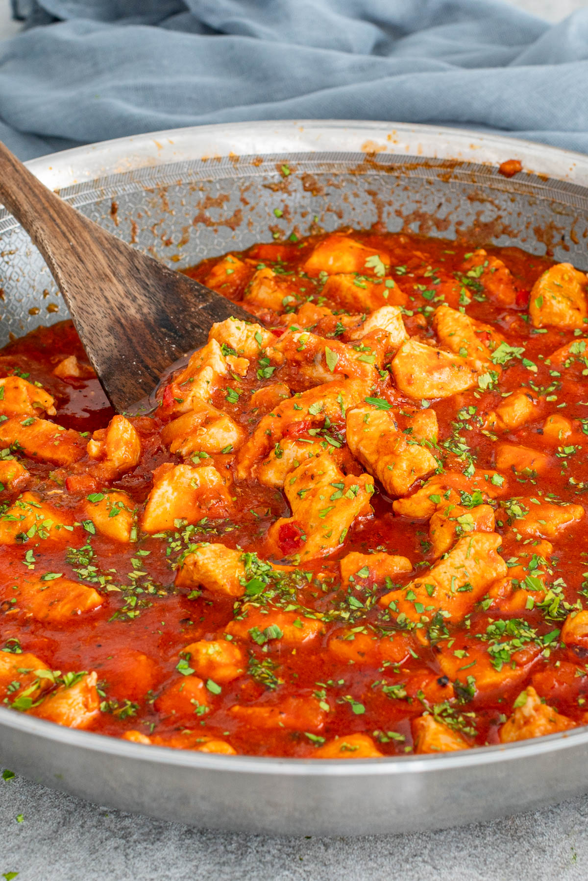 Tocăniță de pui &icirc;n sos de roșii, gătită &icirc;ntr-o tigaie.