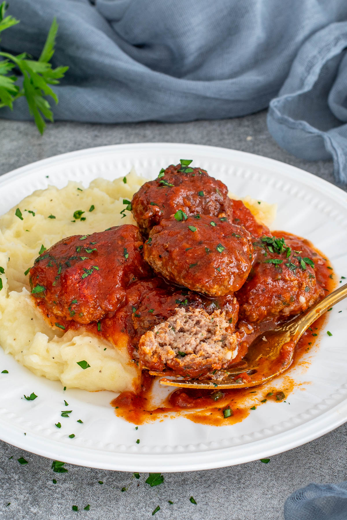 Chifteluțe marinate &icirc;n sos de roșii cu piure de cartofi, servite pe farfurie.