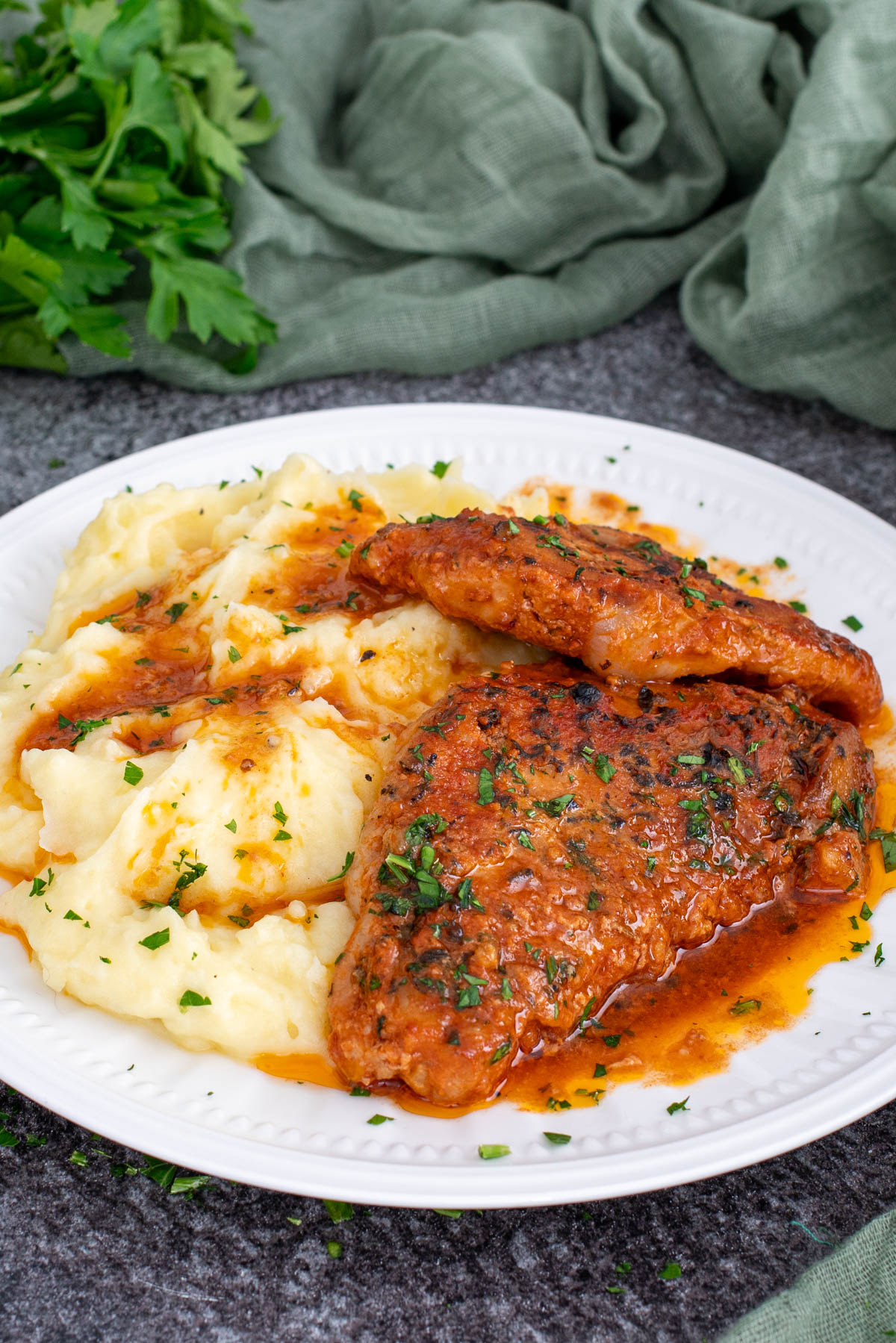 Cotlete de porc cu sos de rosii si usturoi, servite alaturi de o portie de piure de cartofi.