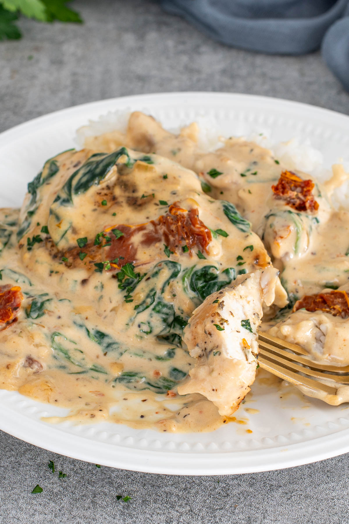 Piept de pui toscan servit pe pat de orez alb, acoperit cu sos cremos, spanac gătit și bucățele de roșii uscate.