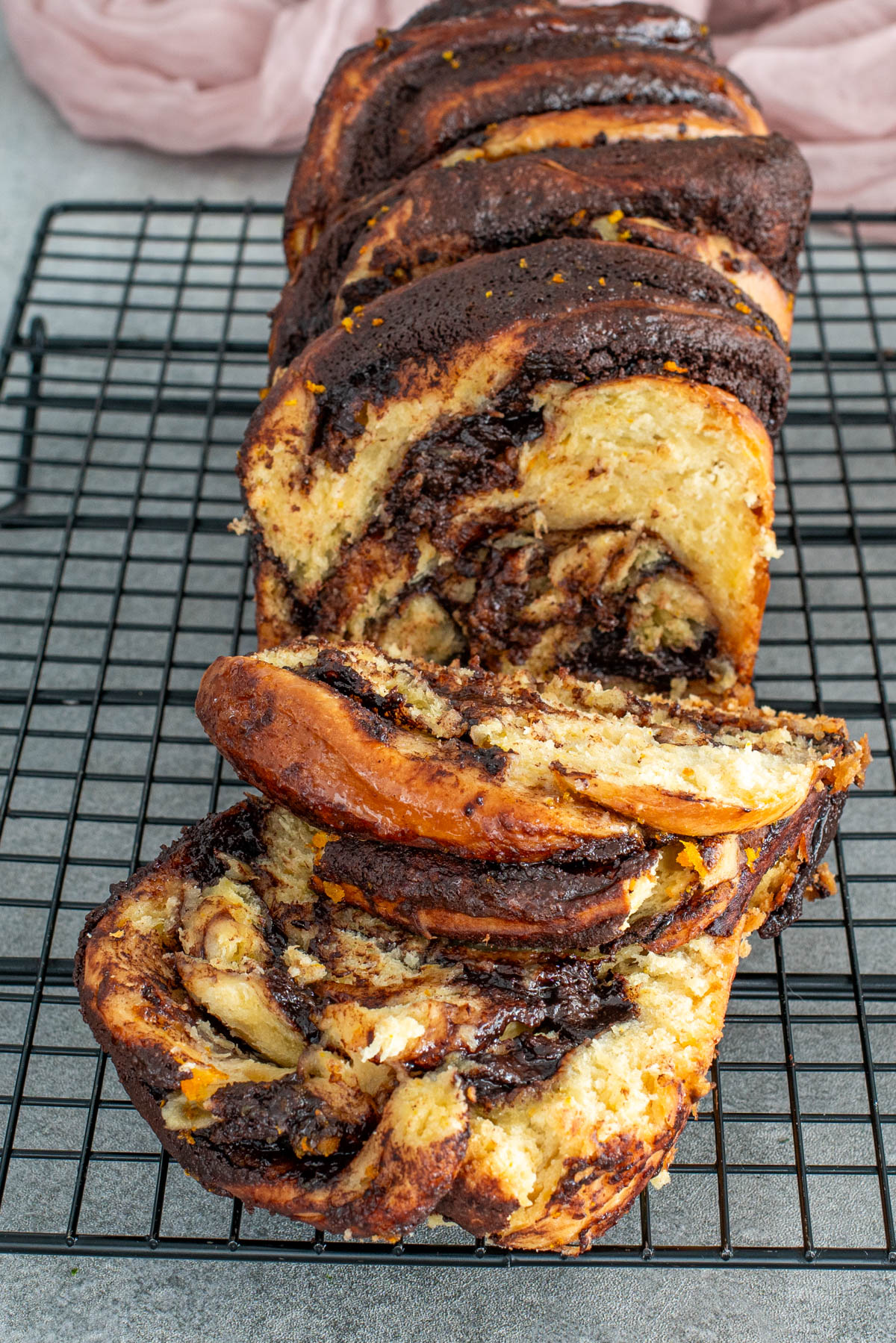 Babka feliată, așezată pe un grătar de răcire, cu straturi vizibile de umplutură.