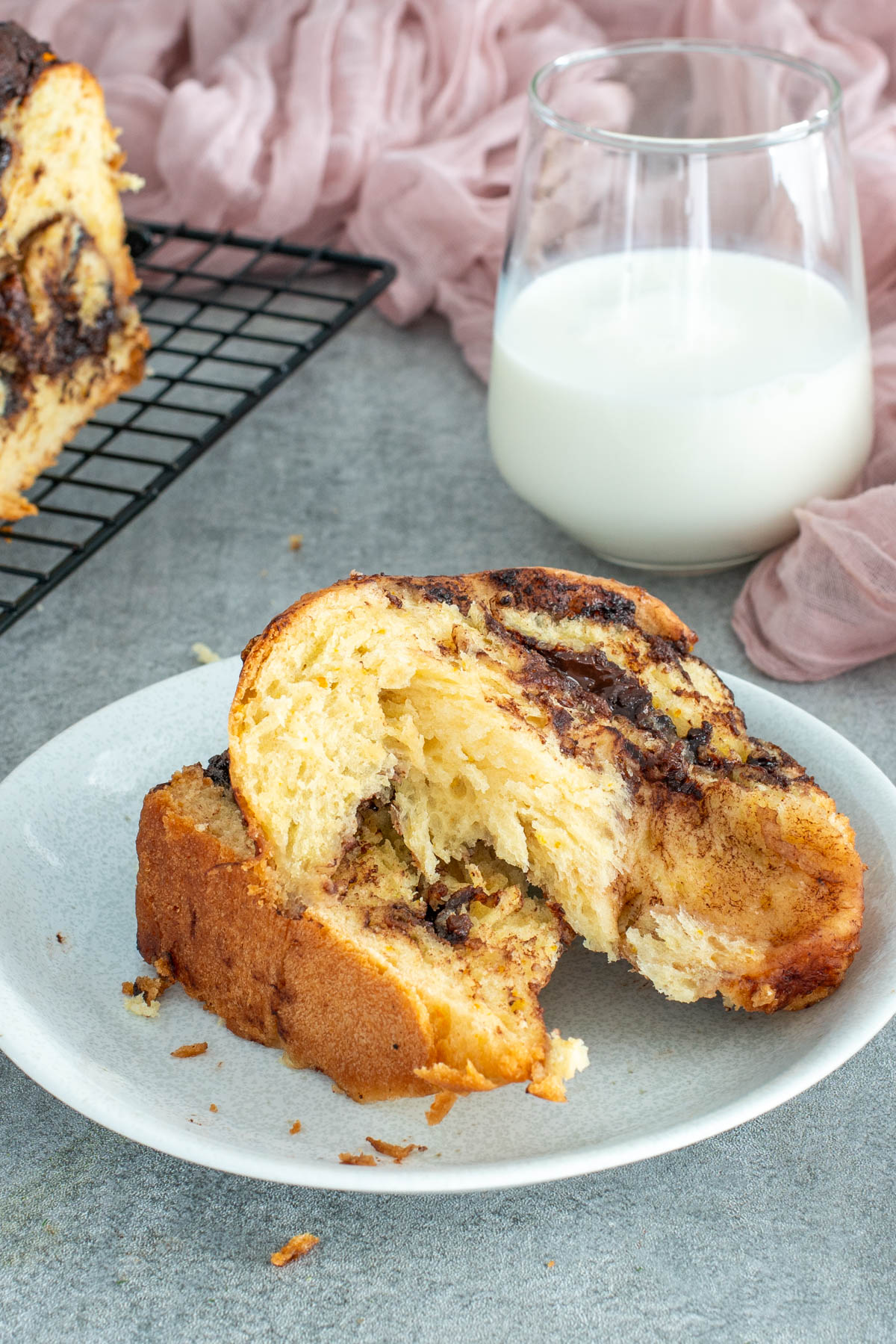 Felie de babka pufoasă ruptă în două, pe farfurie, cu umplutură bogată și textură aerată.