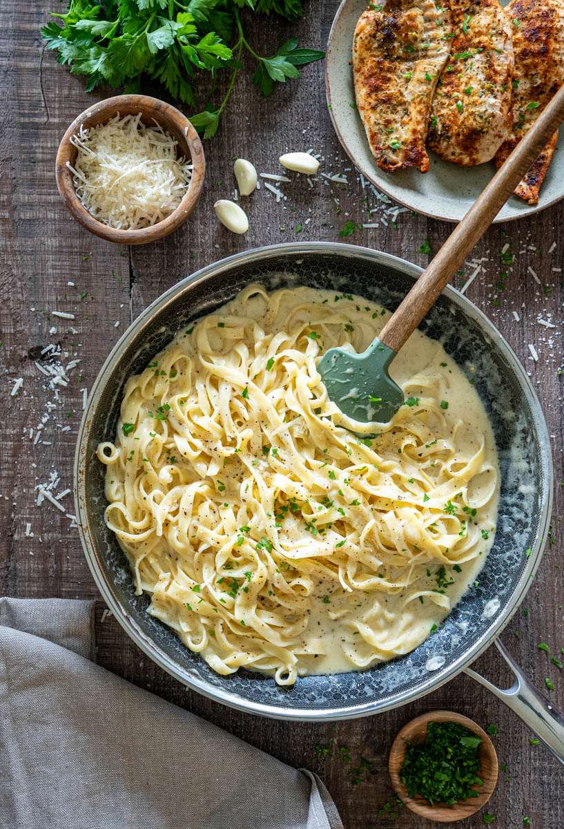 Tagliatelle în sos de smântână și parmezan, servite cu piept de pui feliat.