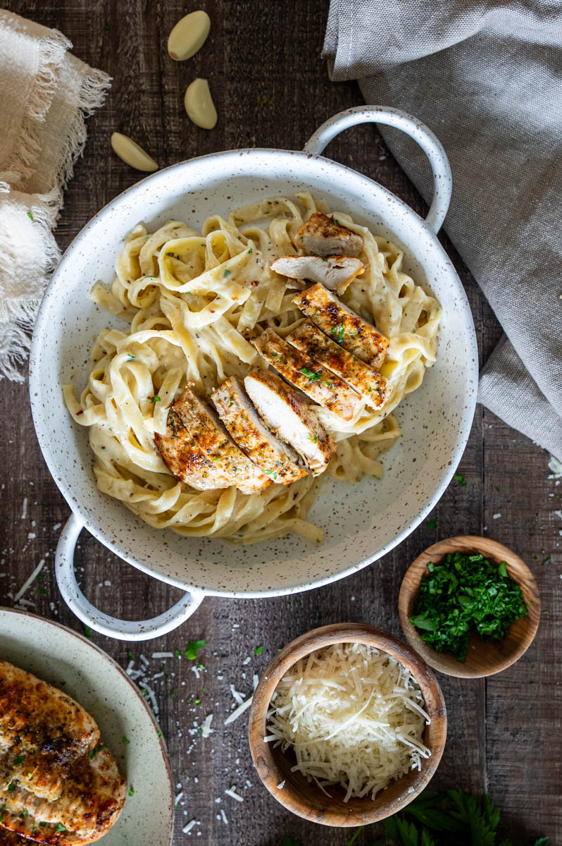 Tagliatelle în sos de smântână și parmezan, servite cu piept de pui feliat.