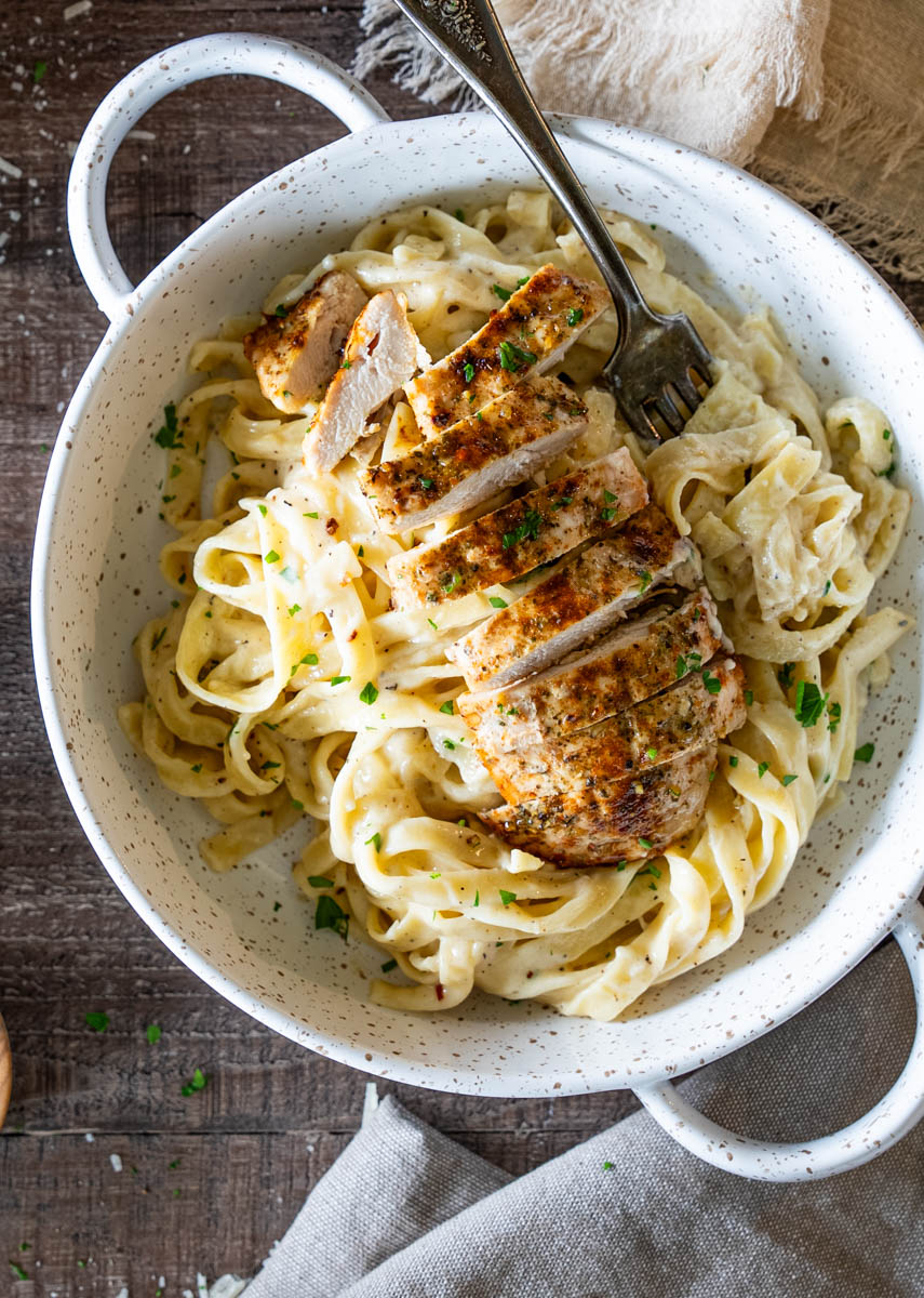 Tagliatelle în sos de smântână și parmezan, servite cu piept de pui feliat.