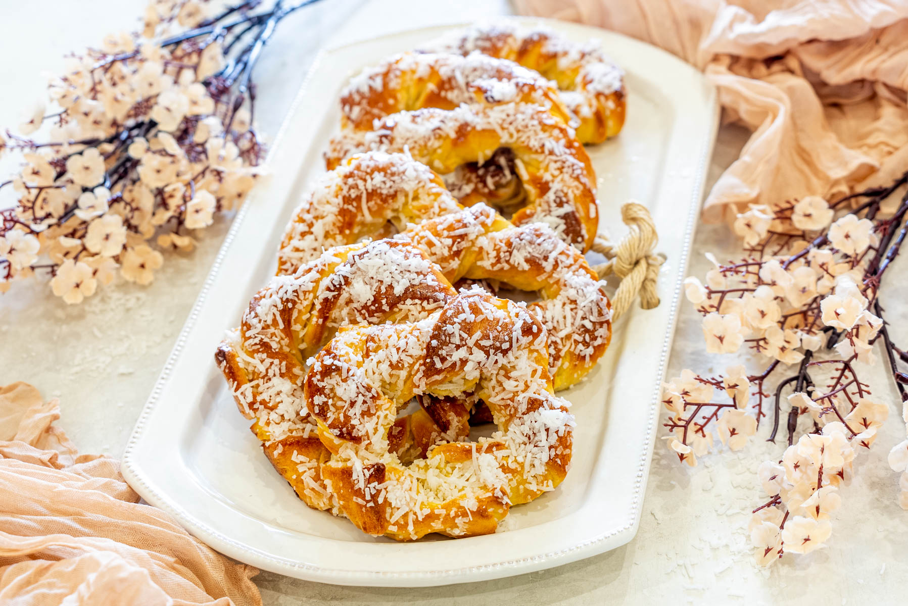 Covrigi &icirc;nsiropați cu cocos, pufoși și &icirc;nsiropați, decorați cu fulgi de cocos pentru un desert delicios.