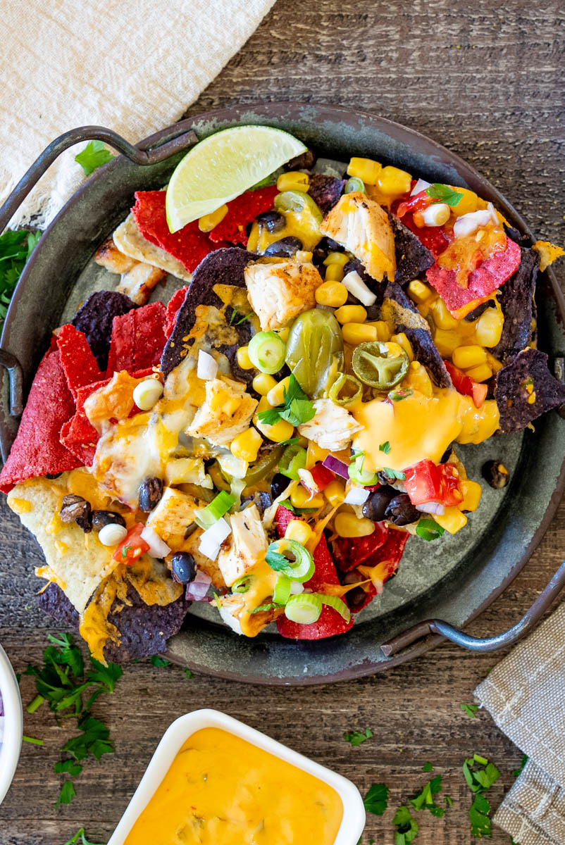 Porție de nachos cu pui, br&acirc;nză topită, jalape&ntilde;o, porumb și fasole neagră, perfectă pentru o gustare sau petrecere.