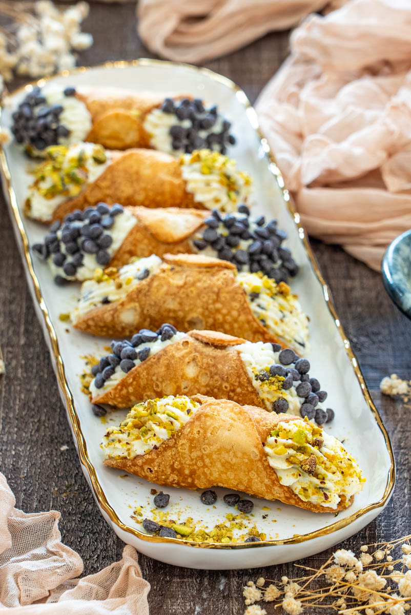 Cannoli de casă cu coajă aurie și crocantă, umpluți generos cu cremă și finisați cu fistic sau chipsuri de ciocolată.