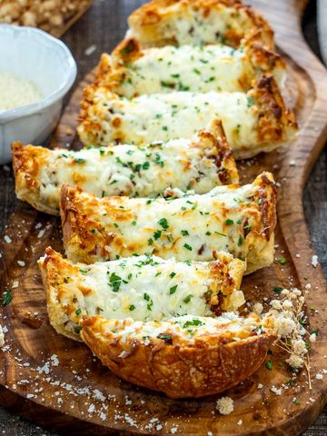 Pâine cu usturoi și mozzarella topită, presărată cu pătrunjel și parmezan.