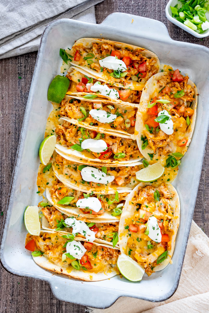 Tacos cu pui suculent și br&acirc;nză topită, umpluți cu roșii proaspete, ceapă verde și sos cremos, rumeniți la cuptor.