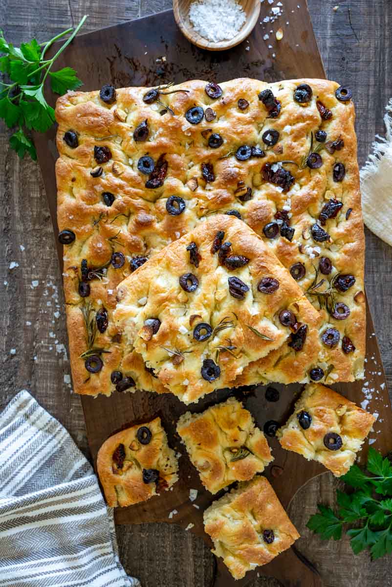 Focaccia pufoasă cu măsline negre și roșii uscate, tăiată în bucăți