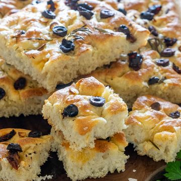 Focaccia pufoasă cu măsline negre, rozmarin și usturoi, tăiată în bucăți
