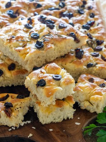 Focaccia pufoasă cu măsline negre, rozmarin și usturoi, tăiată în bucăți