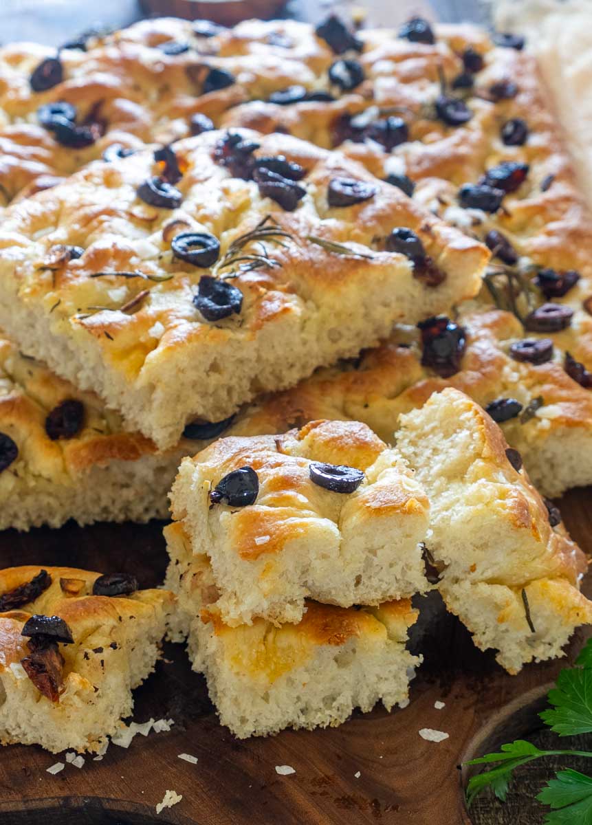 Bucăți de focaccia pufoasă cu miez aerat, măsline negre și rozmarin