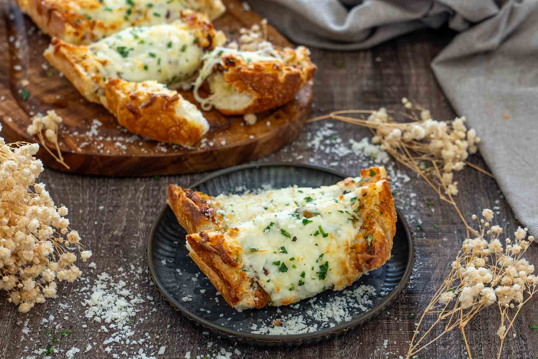 P&acirc;ine cu usturoi și mozzarella topită, servită pe farfurie cu parmezan și pătrunjel.