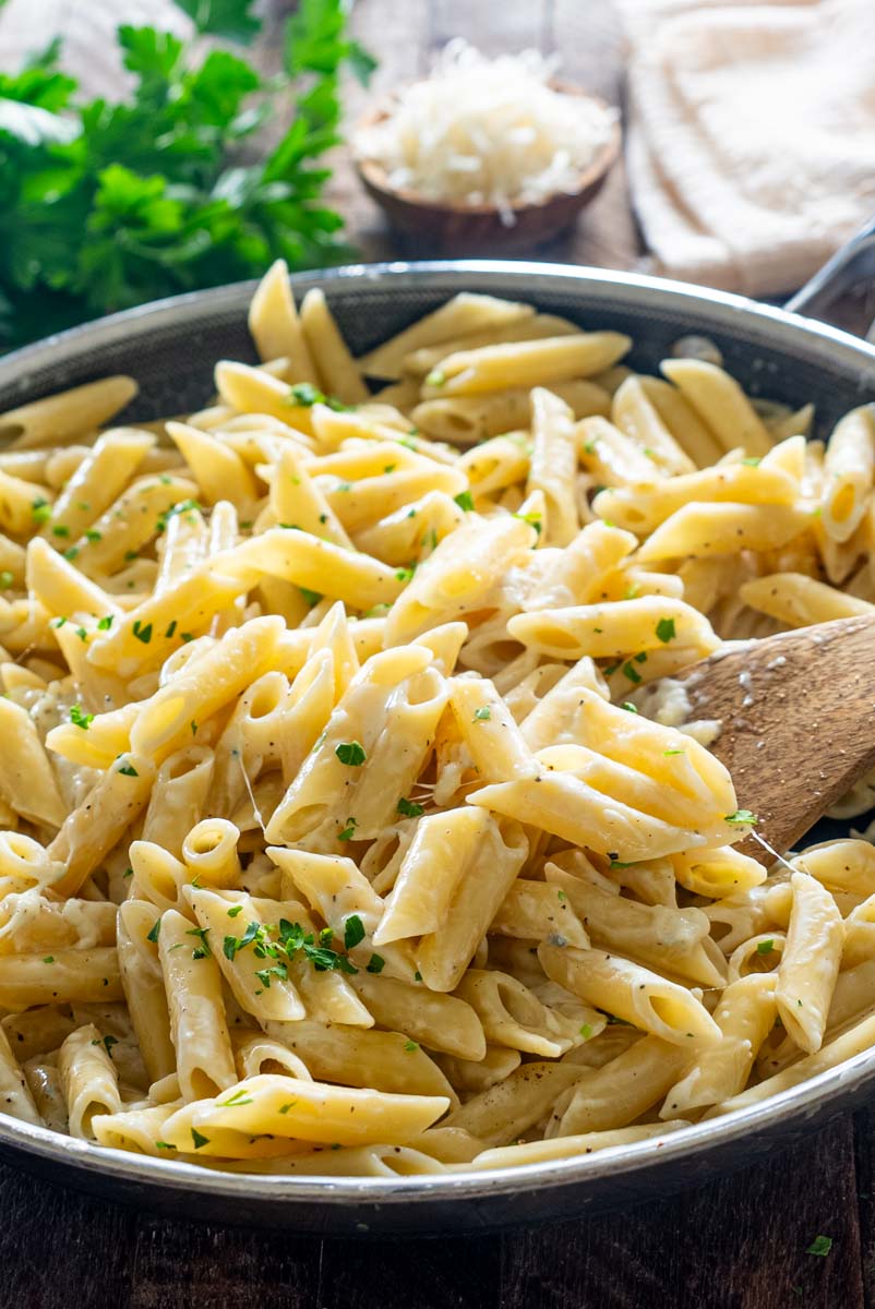 Paste penne Quattro Formaggi amestecate în tigaie cu sos cremos de brânzeturi.