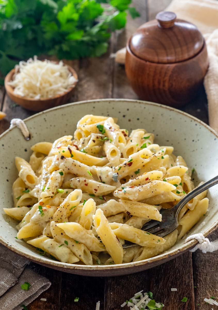 Porție de paste penne Quattro Formaggi cu sos cremos, pătrunjel, piper și fulgi de chilli.