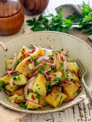 Salată germană de cartofi cu bacon crocant, ceapă roșie și verdeață.