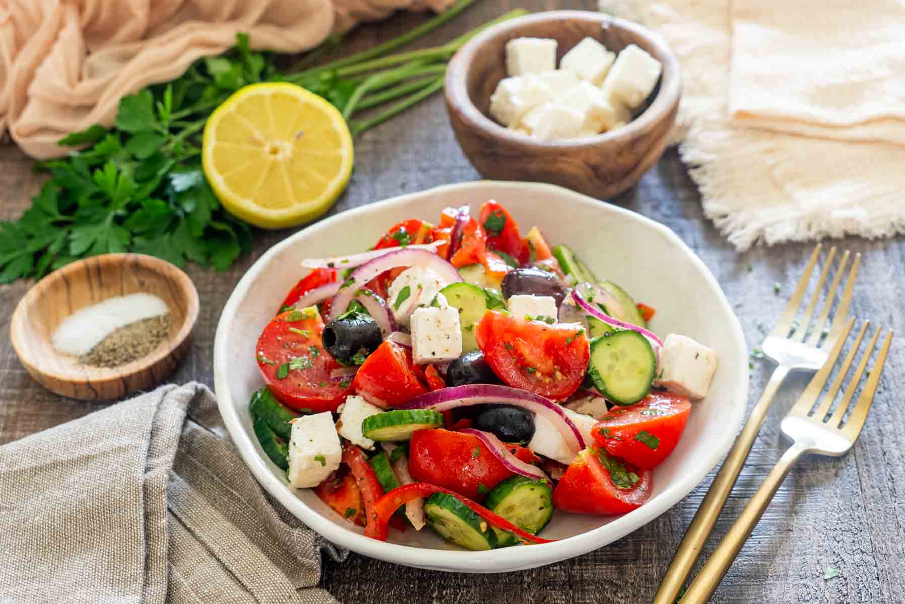 Bol alb cu salată bulgărească din roșii, castraveți, ardei, ceapă roșie, măsline și cuburi de br&acirc;nză.